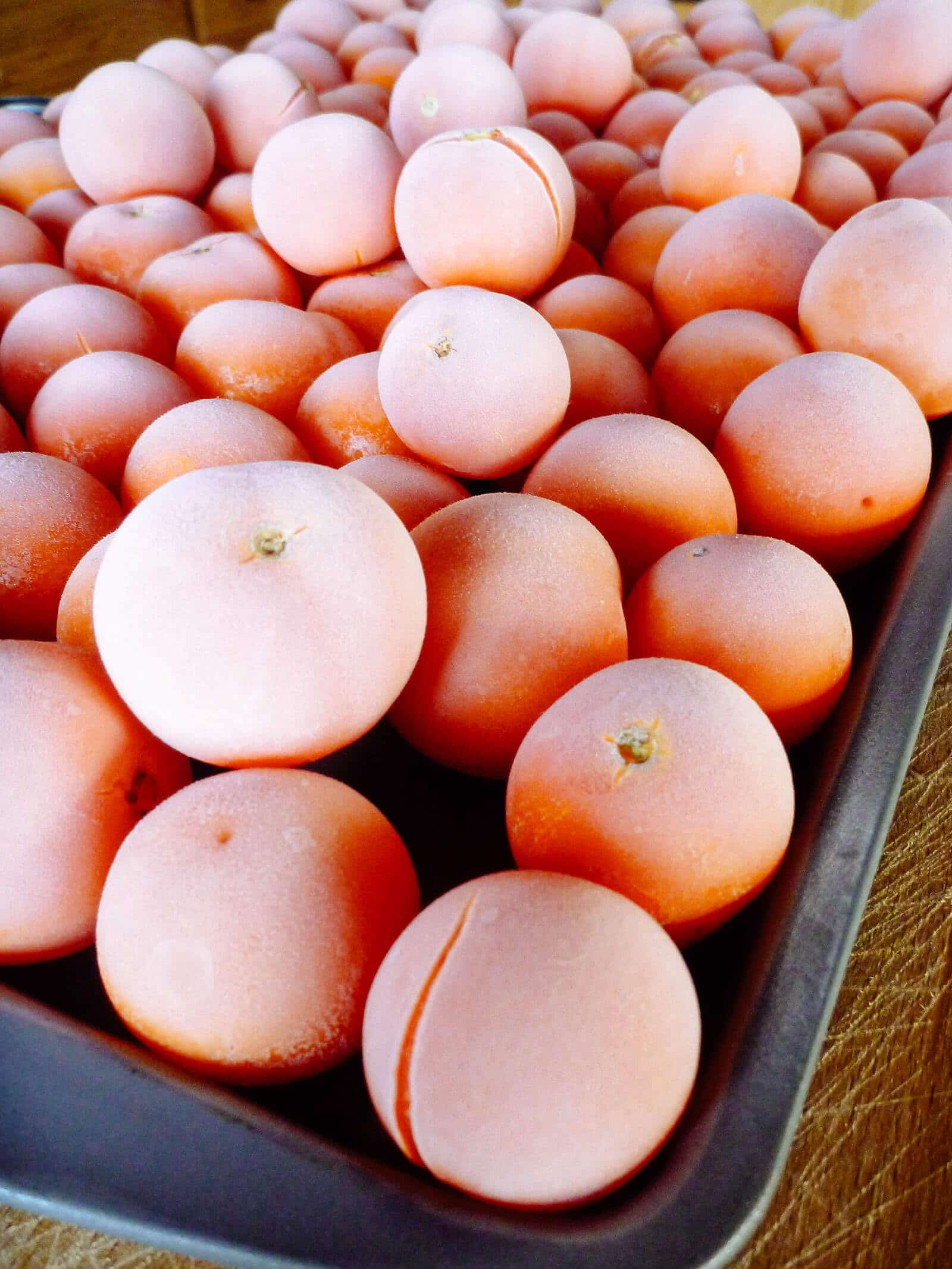 A baking sheet filled with frozen whole tomatoes