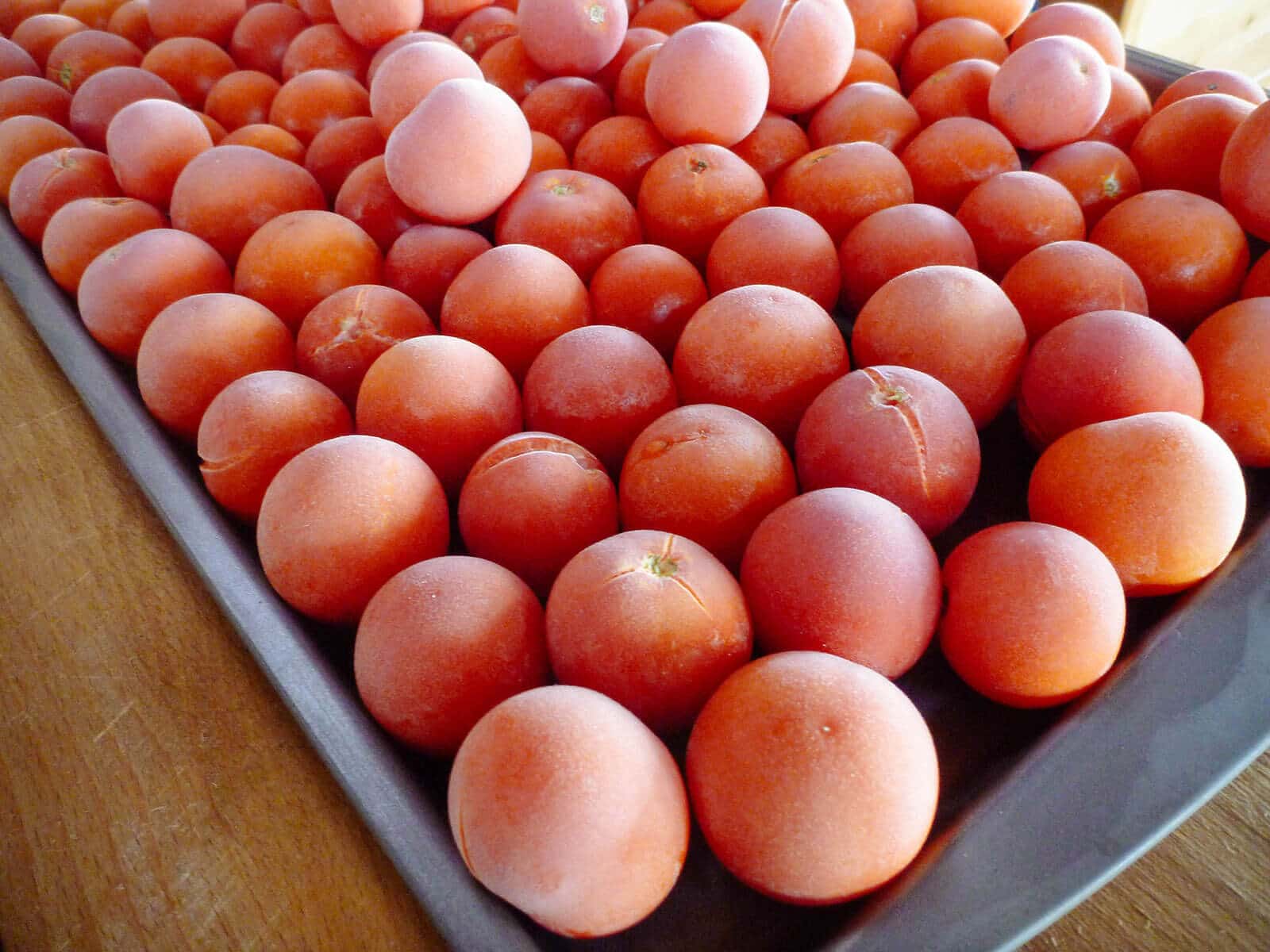 Frozen whole tomatoes on a baking sheet